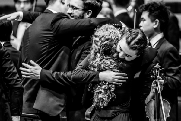 Black and white photo of musicians hugging following the end of a concert